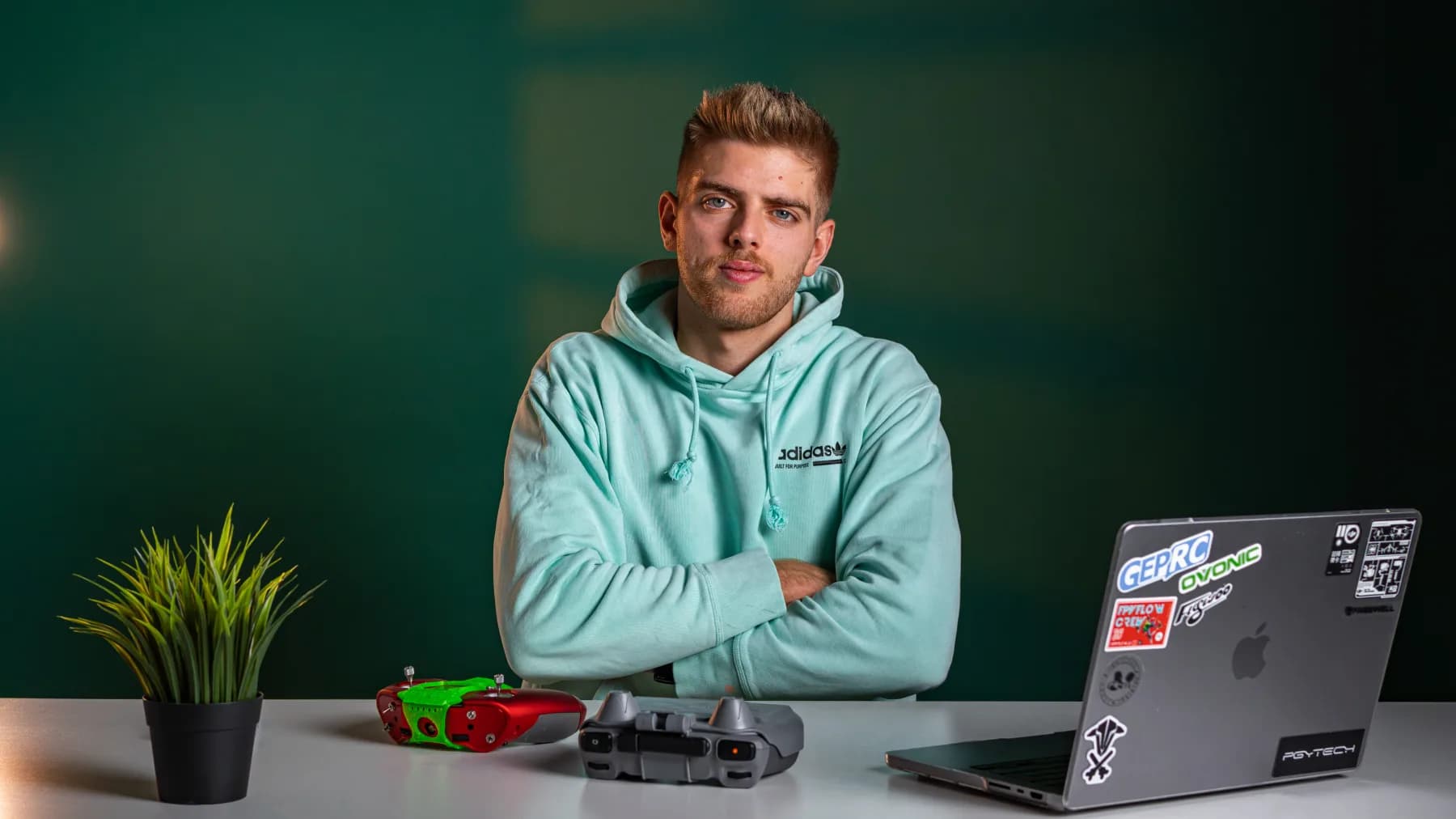 Elia Zanetta alla sua scrivania con visore FPV, radiocomando per drone e un laptop coperto di adesivi.