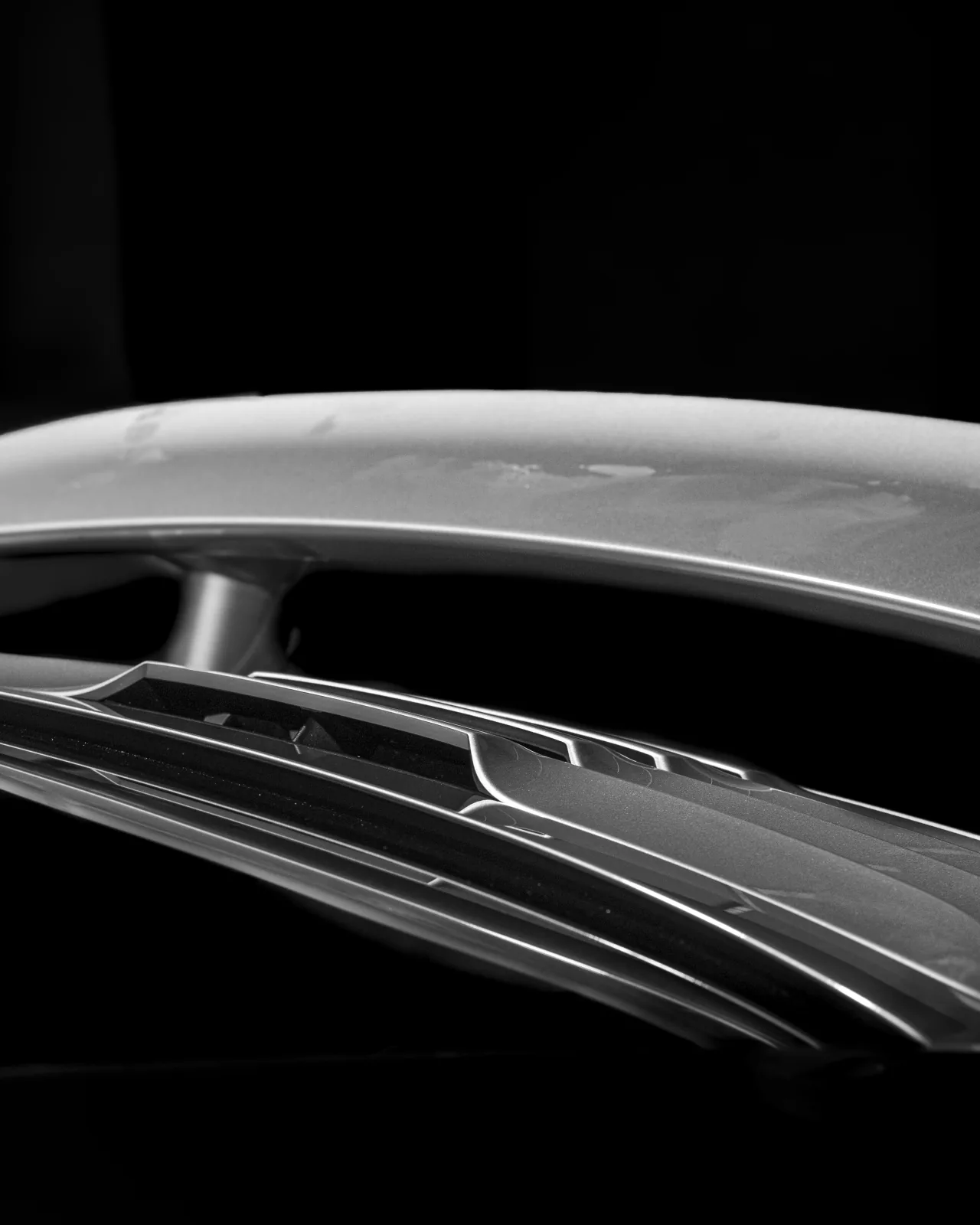 Dettaglio in bianco e nero dello spoiler posteriore di un’auto.