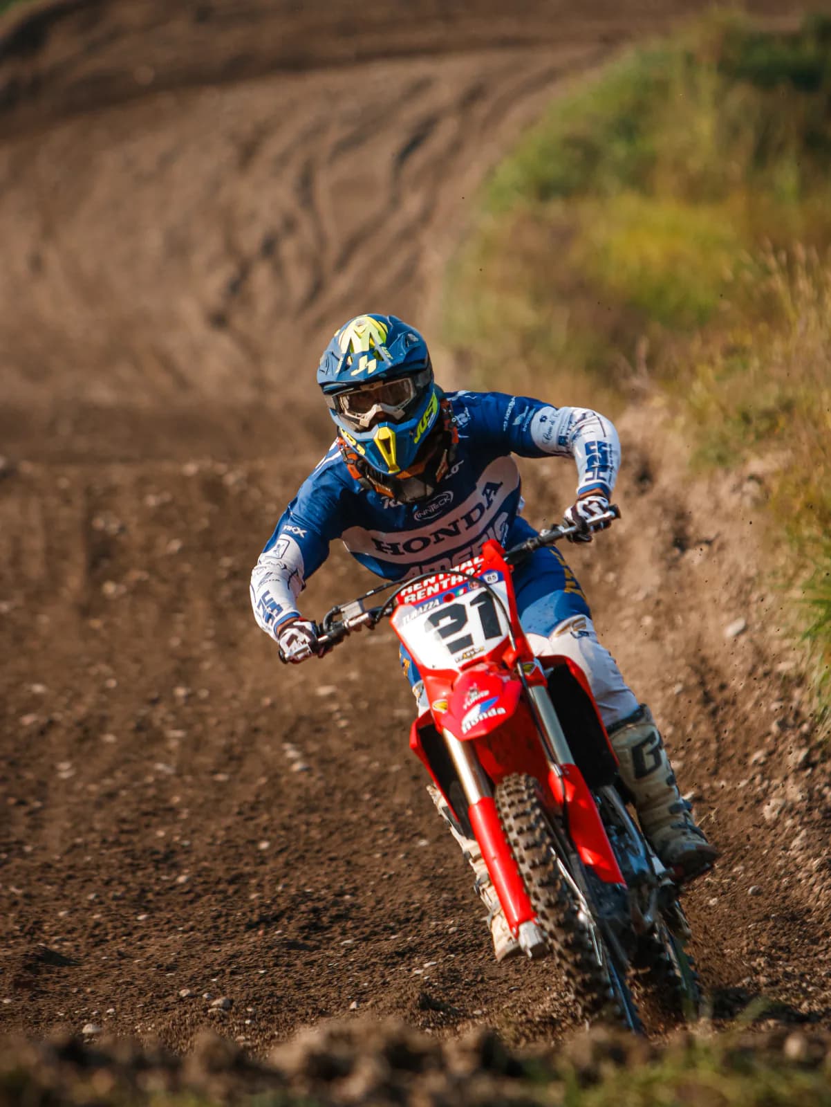 Pilota di motocross su Honda in curva su sterrato.